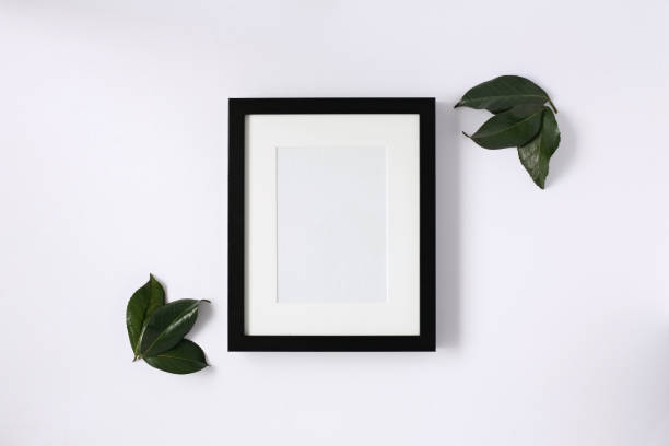 Flat lay mock up of black photo frame with leaves.