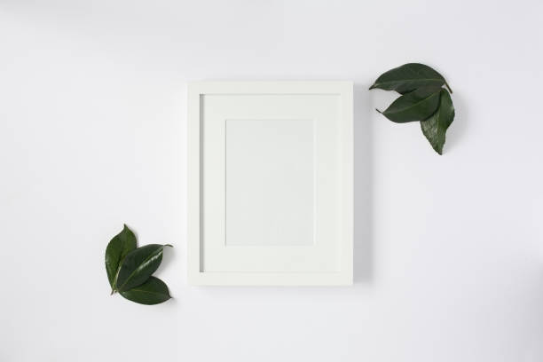 istock Flat lay mock up of white frame with leaves. 699087376