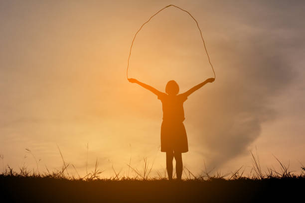 istock Silhouette Girl Playing Skipping On Field Against Sky During Sunset 699169233