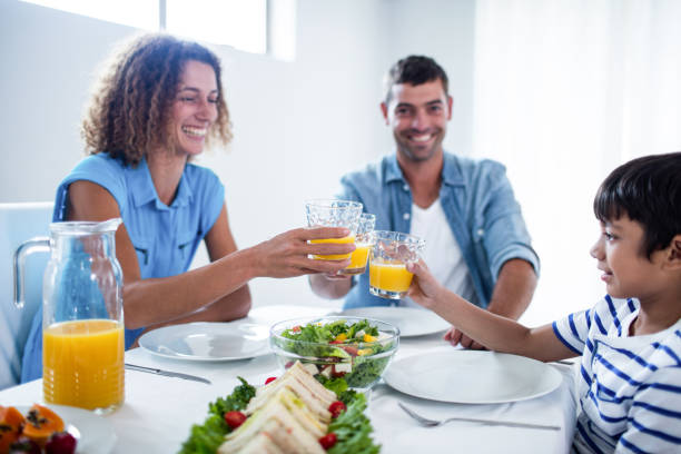 istock Family toasting glasses of orange juice while having breakfast 699178024