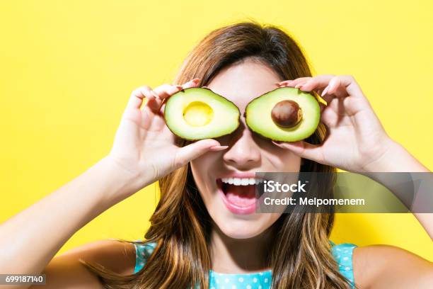 Happy Young Woman Holding Avocado Halves Stock Photo - Download Image Now - Avocado, Vegan Food, One Woman Only