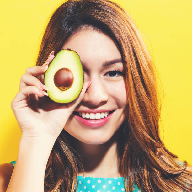 istock Happy young woman holding avocado halve 699187190