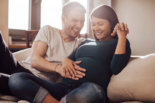 Husband touching wife's stomach, trying to feel baby.