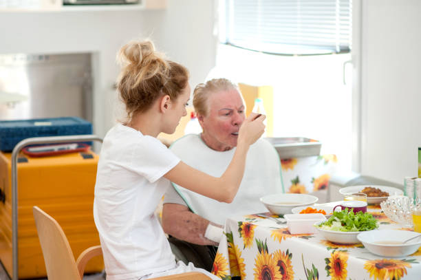 nurse in the nursing home helping senior woman eating - senior adult nursing home eating home interior imagens e fotografias de stock