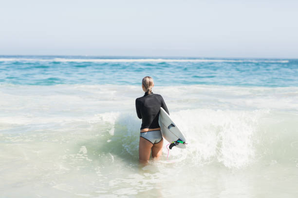 istock Woman with surfboard walking towards sea 699281918