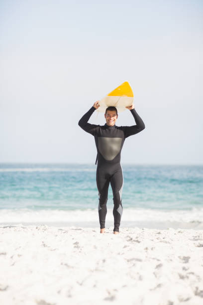 istock Happy man holding surfboard over head 699311404