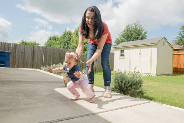 Mother with Baby Learning to Walk in Backyard USA
