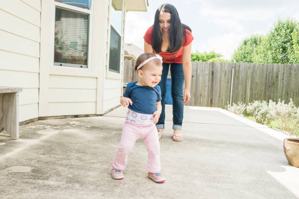istock Mother with Baby Learning to Walk in Backyard USA 699363966