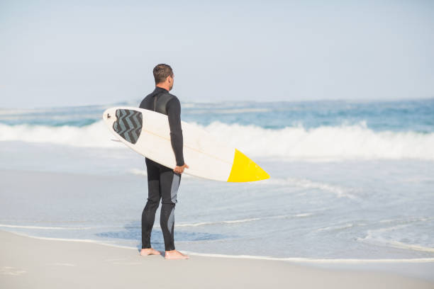 istock Rear view of man with surfboard standing on the beach 699368746