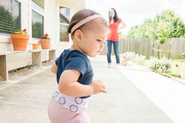 istock Millennial Mother Watches Baby's First Steps in Backyard USA 699369052