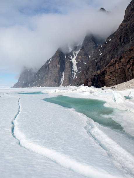 istock Mountains with dramatic Arctic sky and sea ice with meltwater 699372618