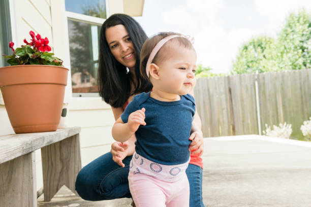 istock Millennial Mother Watches Baby's First Steps in Backyard USA 699373380