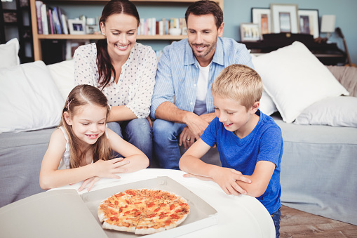 Smiling family with pizza on table at home