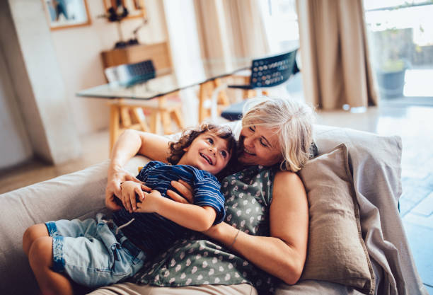 Beautiful grandma and grandson playing together having fun at home Grandmother and grandson sitting together at home spending time playing, embracing and laughing grandson stock pictures, royalty-free photos & images