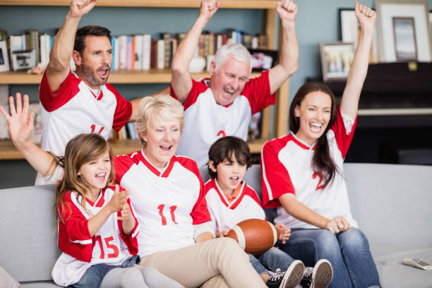lächelnd familie mit großeltern amerikanischen fußballspiel ansehen - sitting 20s adult american football stock-fotos und bilder