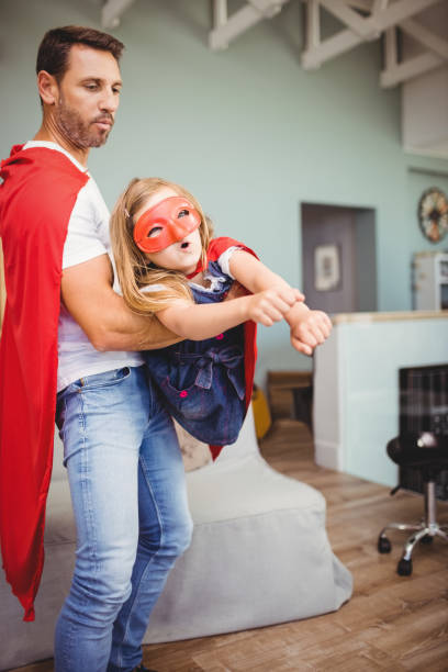 istock Father holding daughter wearing superhero costume 699551604