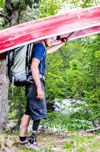 istock Man with prosthetic leg carrying his canoe to the river 699564778