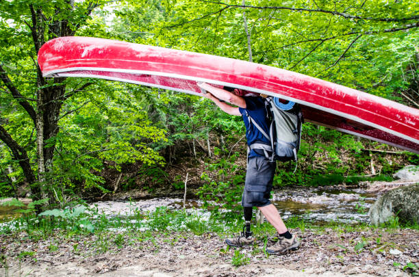 istock Man with prosthetic leg carrying his canoe to the river 699565198