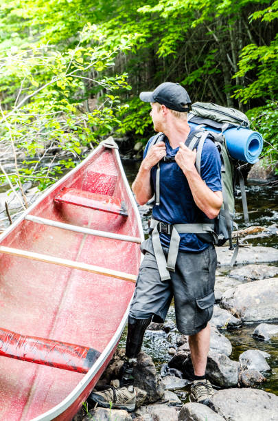 istock Man with prosthetic leg standing by his canoe close to the river 699570464