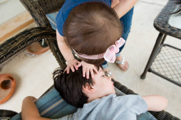 Baby Sister Reachess Down to Touch Brother's Head