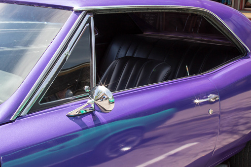 View through the driver's side window of a purple muscle car with black interior
