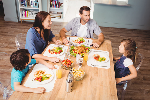 Family discussing with food on dining table at home
