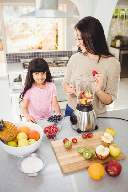 istock Smiling mother and daughter preparing fruit juice 699596604