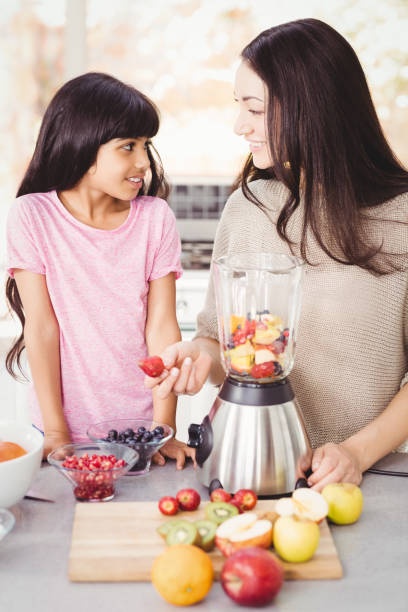 istock Cheerful mother and daughter preparing fruit juice 699596786