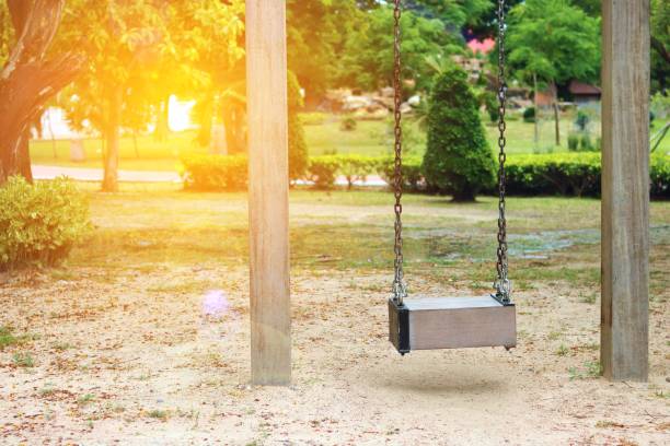 istock Select focus, Empty wooden swing in playground with lens flare effect 699603194