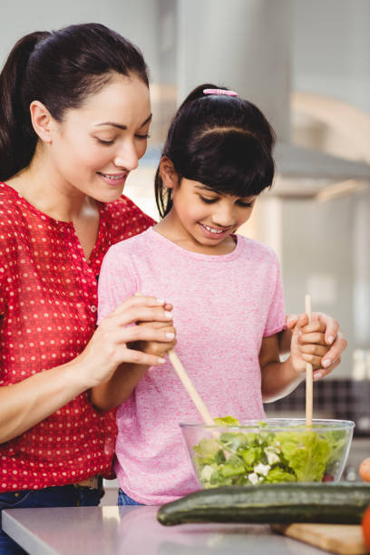 istock Smiling mother and daughter preparing salad 699648810