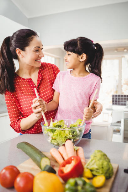 istock Happy mother and daughter preparing salad 699650972