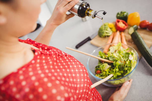 istock Midsection of woman adding oil in salad 699651276