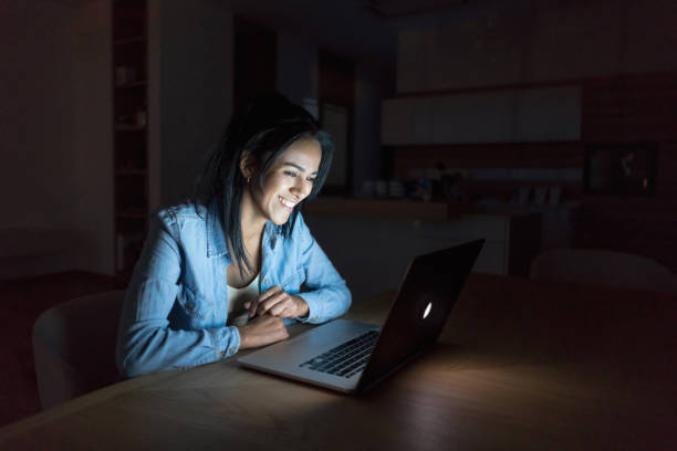 istock Happy woman using her laptop computer at nighttime 699703604