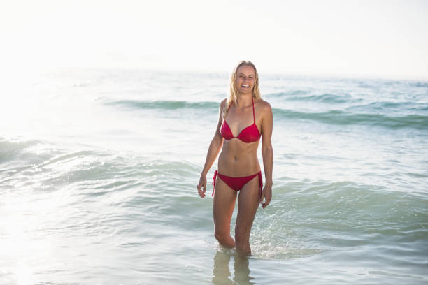 istock Young woman in bikini standing in water 699712916