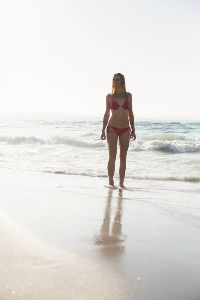 istock Young woman in bikini standing on the beach 699712966
