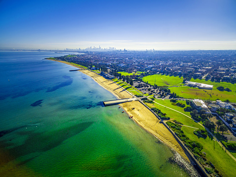 Aerial view of coastline beaches near Elwood with Melbourne CBD skyscrapers in the distance on bright sunny day. Melbourne, Australia
