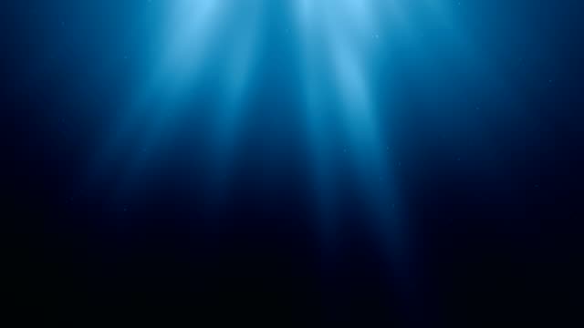 Sunlight rays shining through ocean surface. View from underwater. 3D rendered seamless loop animation.