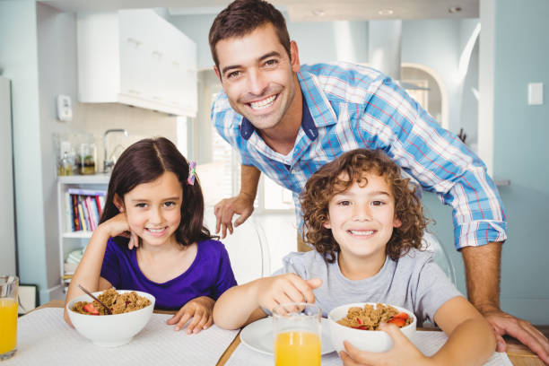 istock Happy man standing by children having breakfast 699738700