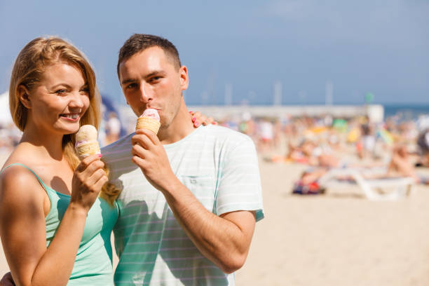 istock Man and woman eating ice cream on beach 699748458