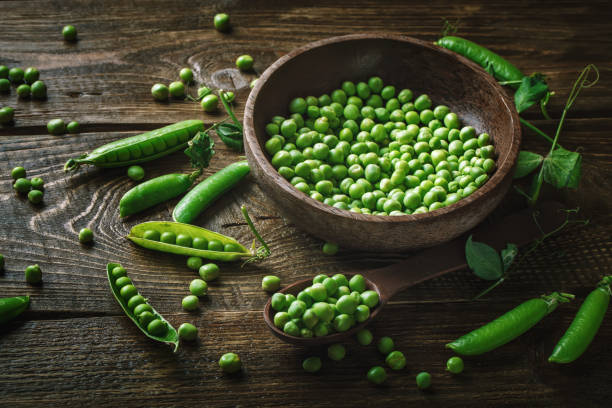 istock Delicious ripe green peas lying on a wooden table 699767126