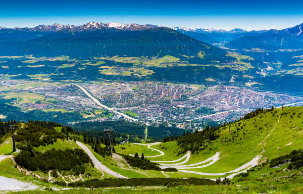 view from above of Innsbruck city with alpes mountain range, Natural path and Cable car take from Seegrube mountain stock photo