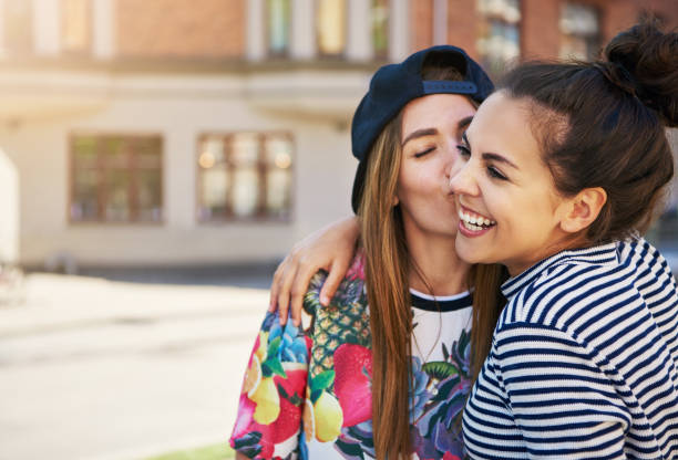 istock Affectionate young woman kissing her friend 699803248