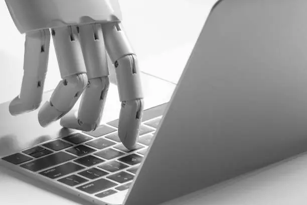 Photo of Chatbot , artificial intelligence , robo advisor , robotic concept. Robot finger point to laptop button.