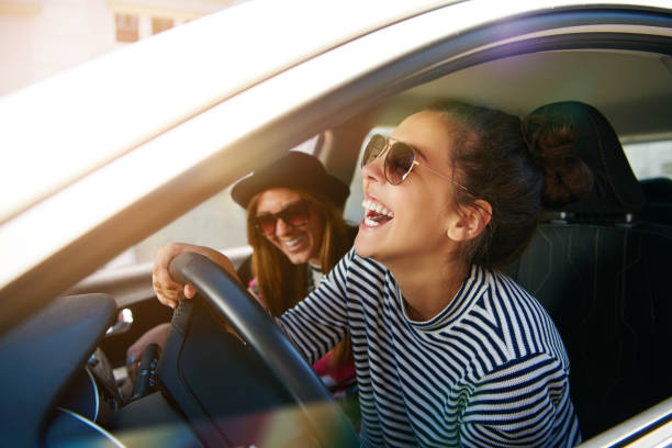 istock Laughing young woman driving a car 699804870