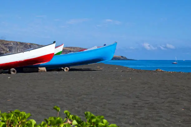 Small fisher boats on the black sand beach in Saint-Paul de la Reunion.