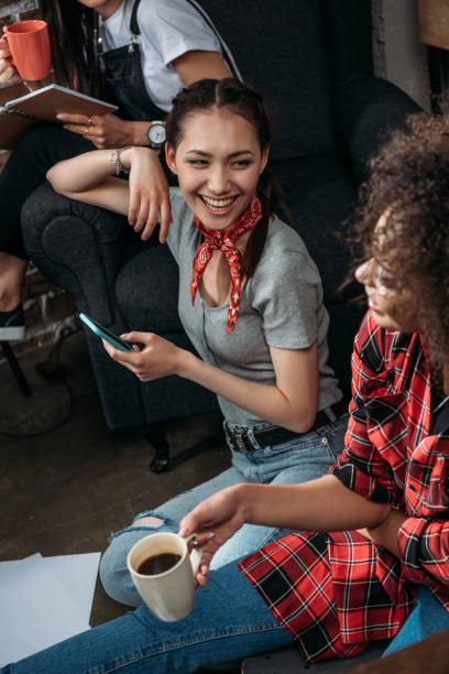 istock Attractive young women with smartphone and coffee cup smiling each other 699821518