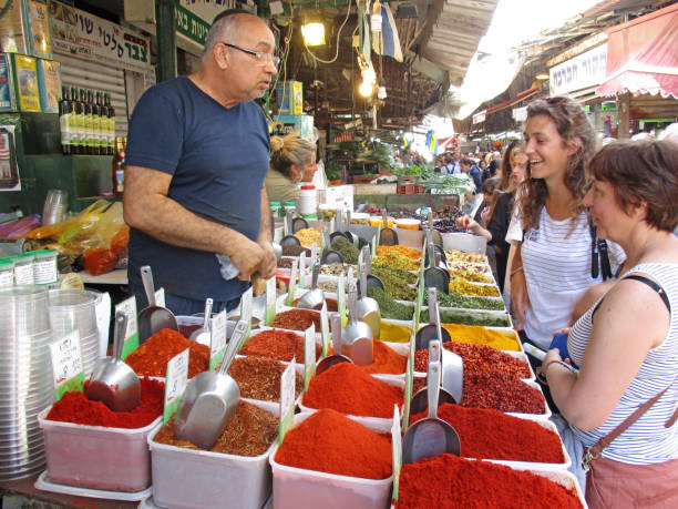 Two women buying fresh spices from a stall Tel Aviv Carmel Market. Also  known as Shuk HaCarmel, is the most famous of all Tel Aviv’s marketplaces. In recent years, it’s even joined the ranks of Tel Aviv’s trendy spots for bars, restaurants, coffee shops and chef-owned food stalls.