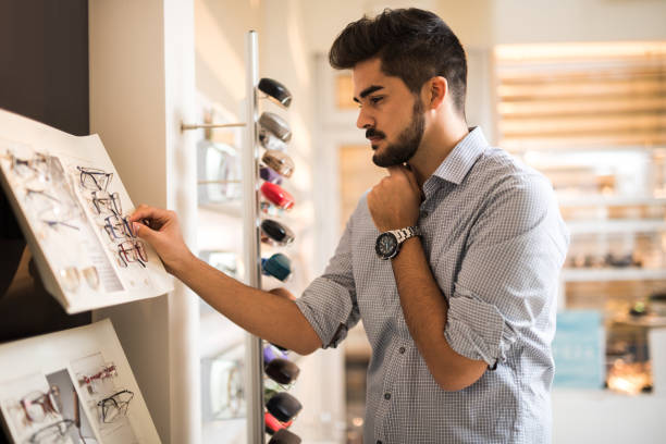 istock Young man choosing new eyeglasses in optician store. 699837444