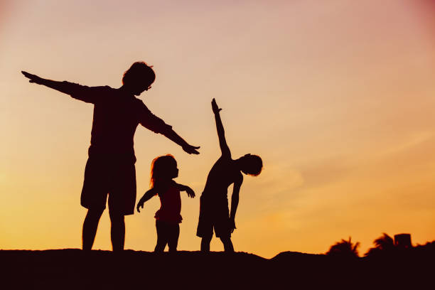 istock father with son and daughter silhouettes play at sunset 699850966