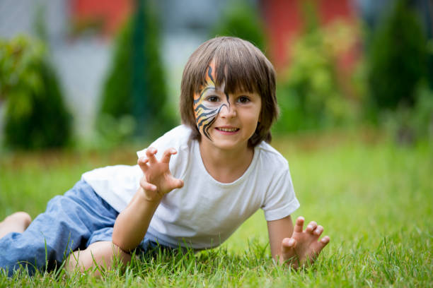 chère enfant d’âge préscolaire, peint comme tigre, jouant dans le jardin - face paint child animal little boys photos et images de collection